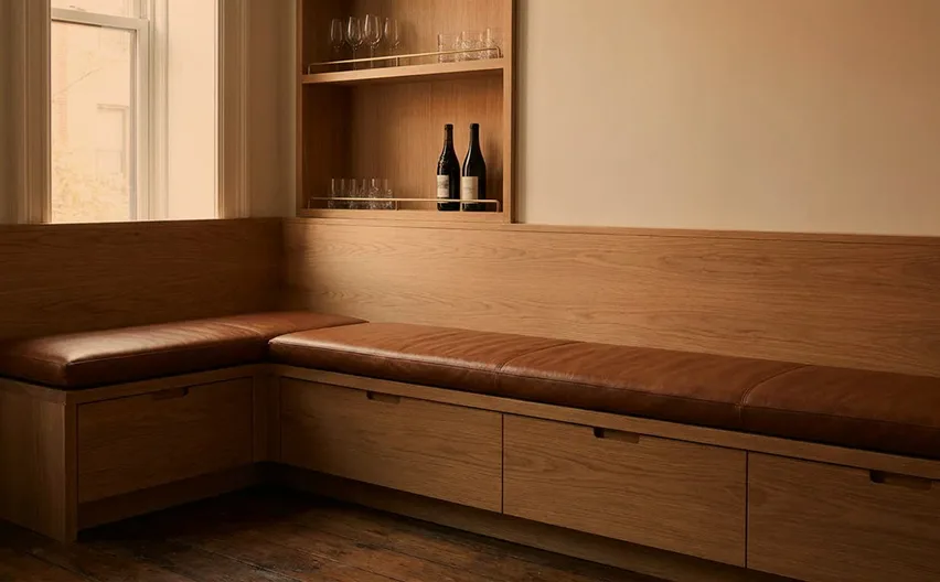 A leather corner banquette beneath an oak wine shelf