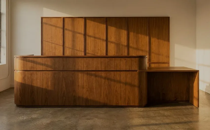 A curved oak reception desk in front of a panelled wall